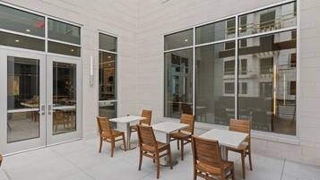 Un amplio patio interior con varias mesas y sillas, ventanas grandes y un diseño moderno y cuidado.
