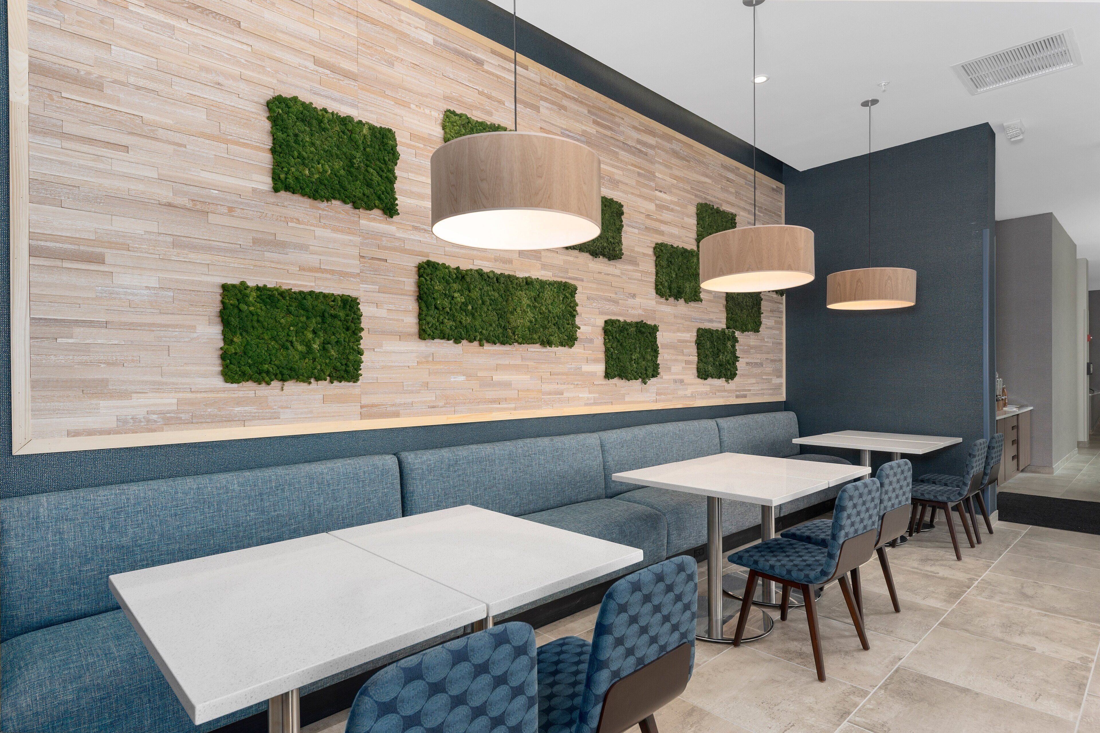 Un intérieur de restaurant moderne avec un long comptoir, des banquettes bleues et un éclairage suspendu.