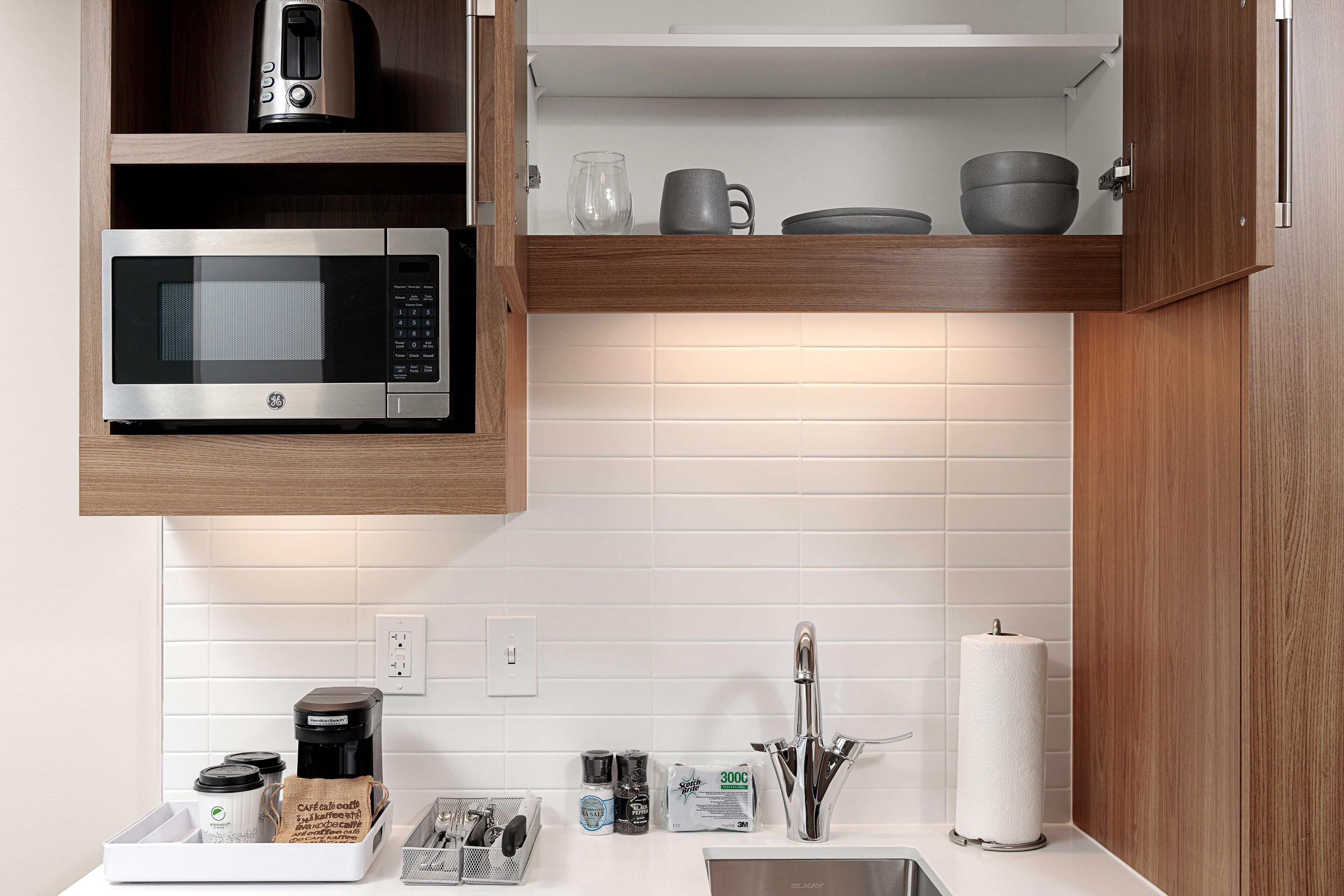 A modern kitchen with a built-in microwave, coffee maker, and a sink with a paper towel holder.