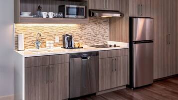 Una cocina moderna con refrigerador de acero inoxidable, lavavajillas y microondas.