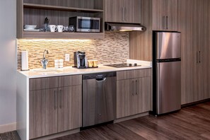 Una cocina moderna con refrigerador de acero inoxidable, lavavajillas y microondas.