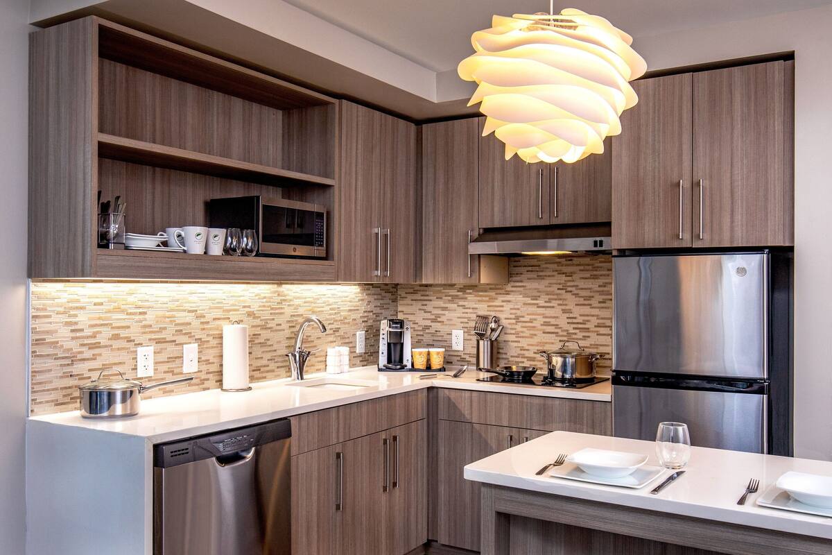 A modern kitchen with wooden cabinets, stainless steel appliances, and a white countertop.