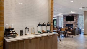 Um hall de hotel moderno com um canto de café, área de estar e lareira.