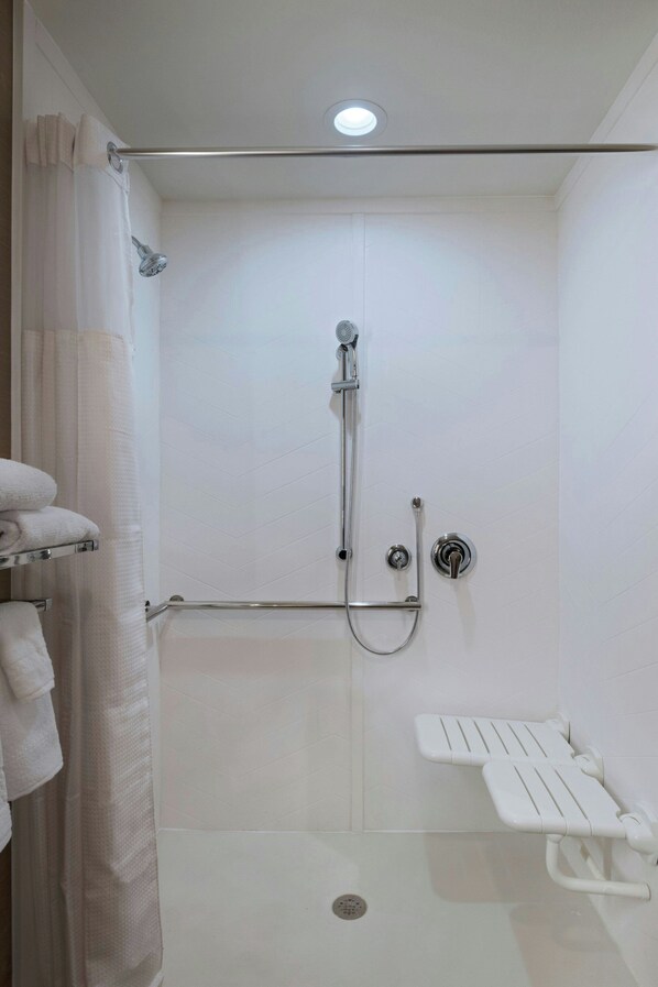 A modern bathroom with a walk-in shower, a white bench, and a towel rack. - Fairfield Inn & Suites by Marriott Colorado Springs East/Ballpark (Colorado Springs)