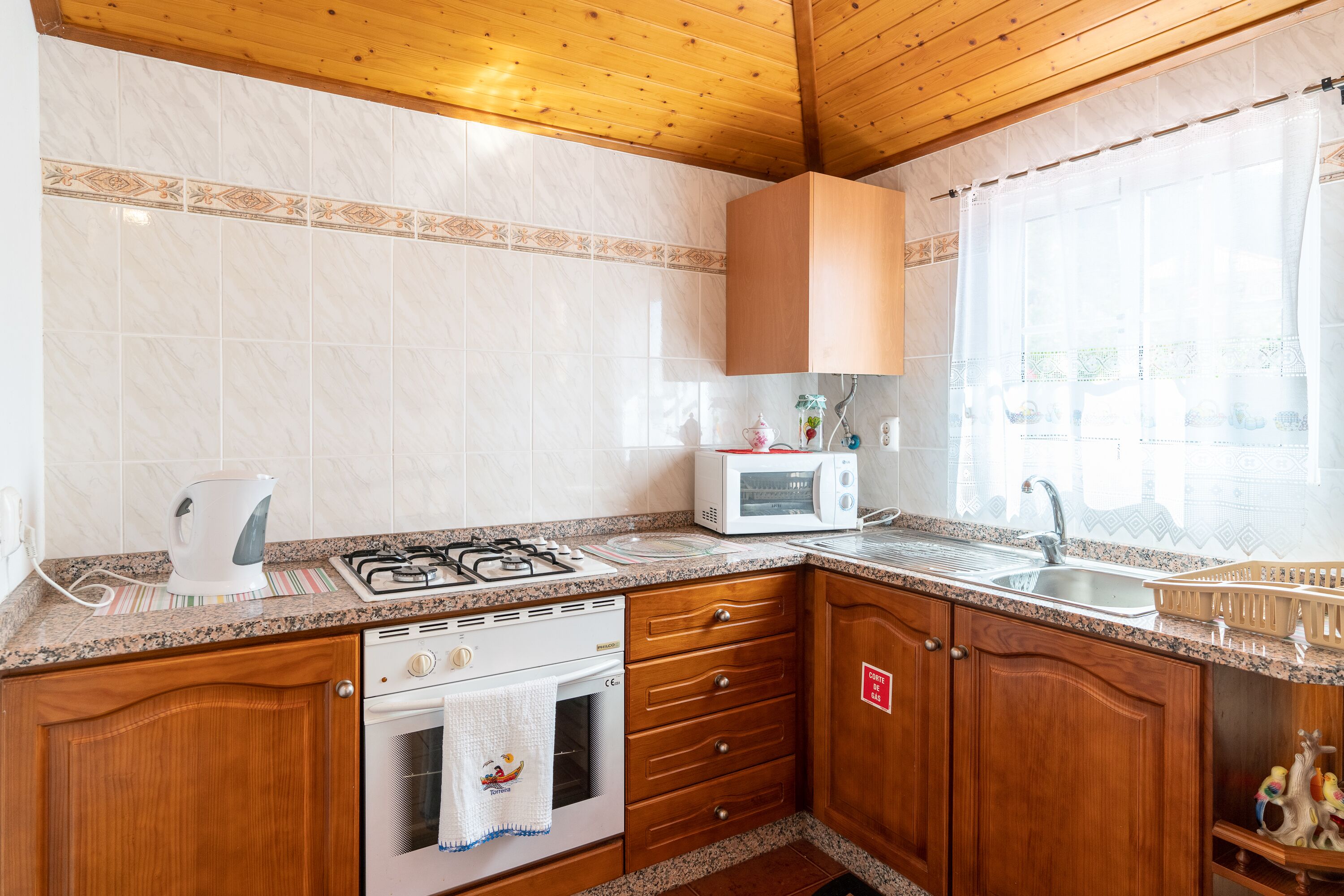 A kitchen with a gas stove, microwave, oven, and wooden cabinets.