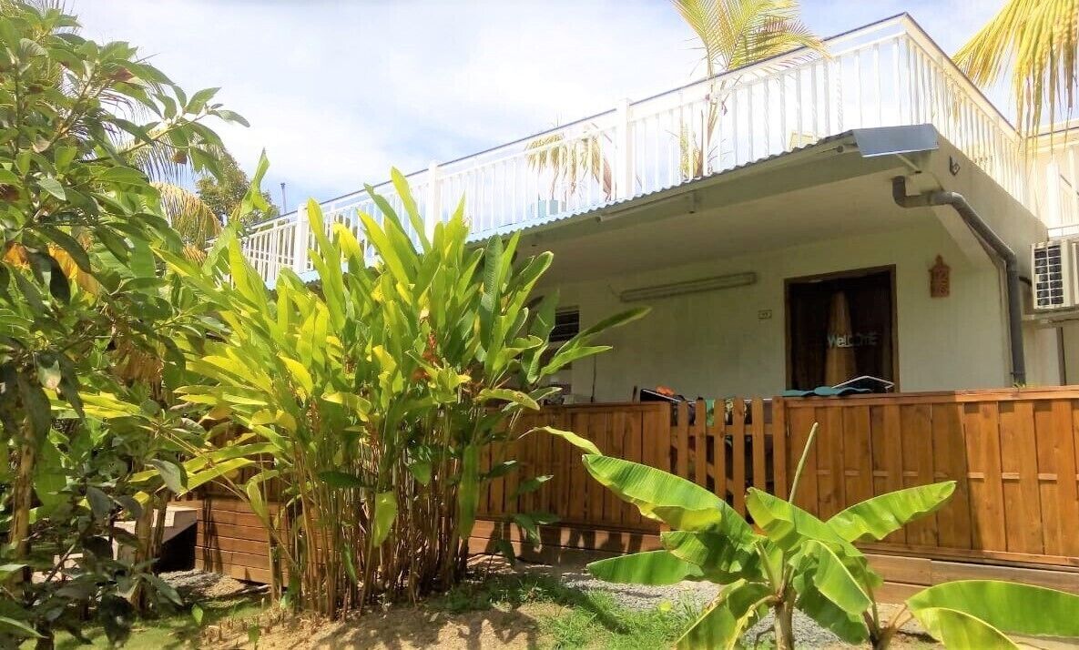 A building with a white exterior, a balcony with a white railing, and a wooden fence.