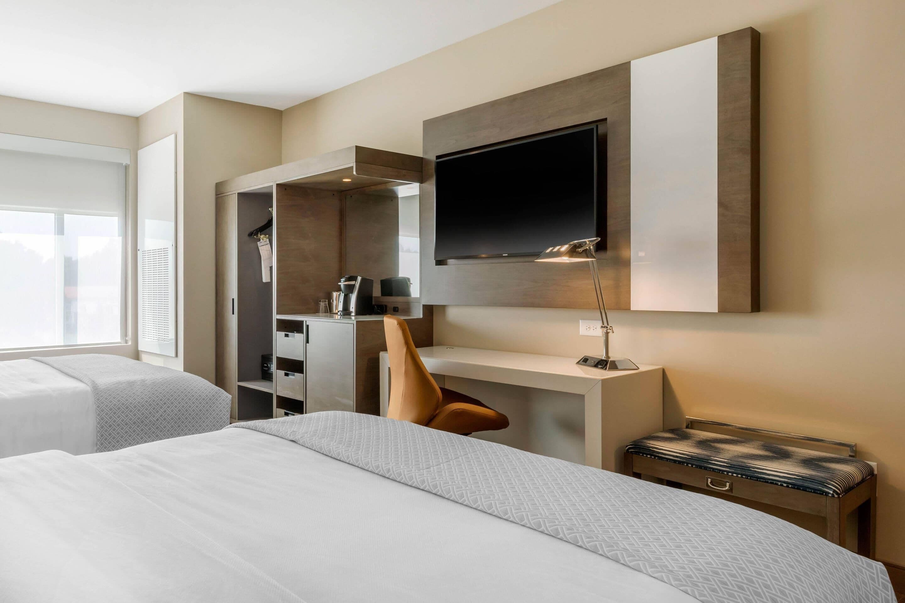 Hotellihuone, jossa on kaksi sänkyä, työpöytä, televisio ja vaatekaappi.