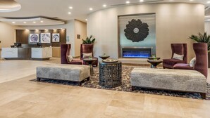 Eine moderne Lobby mit einer Rezeption, einer Sitzecke und einer dekorativen Wandgestaltung.