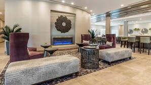 Eine moderne Lobby mit Sitzgelegenheiten, einem Kamin und einem Essbereich.