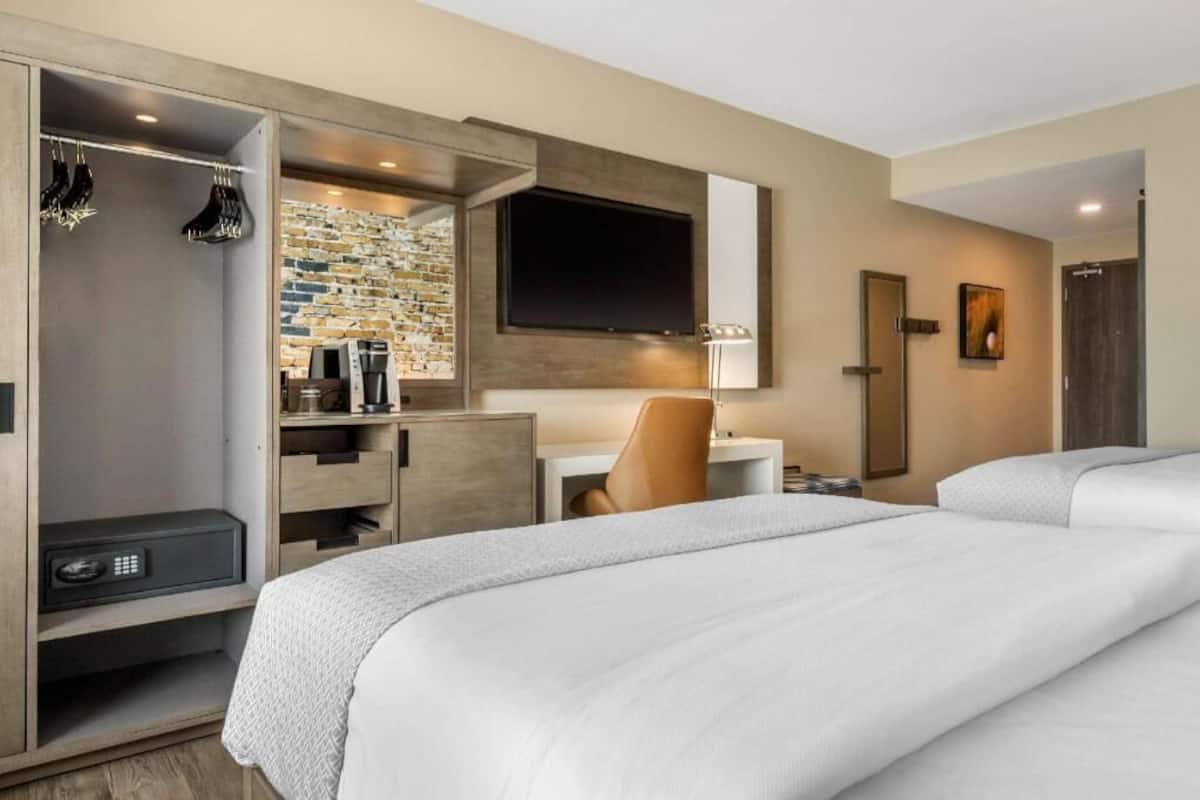 A hotel room with a bed, a desk, a chair, a TV, and a wardrobe.