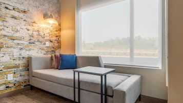 A room with a brick wall, a window, a sofa, and a small table.
