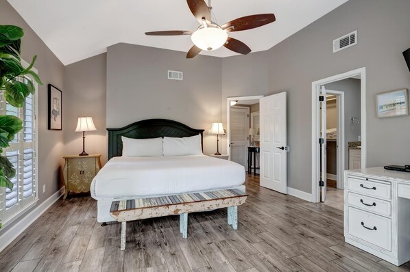 A bedroom with a bed, bedside lamps, a ceiling fan, and a wooden bench.