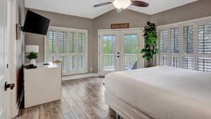 Una camera da letto con un letto, una scrivania, una TV, una ventola a soffitto e un cartello con la scritta 'Beach House'.