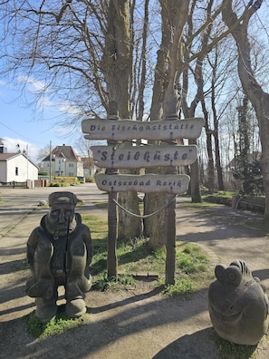 Un cartel de madera con indicaciones direccionales y una escultura de una figura.