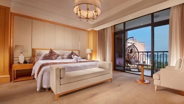 Un dormitorio amplio con una cama grande, una zona de estar y un balcón con vistas.