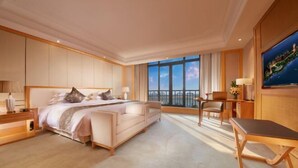 Una habitación de hotel con una cama grande, un escritorio y vistas a la ciudad por la ventana.