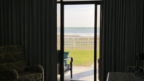 Una habitación con vistas al océano a través de un ventanal corredero.