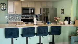 Una cocina moderna con una isla central, taburetes de bar y un refrigerador.
