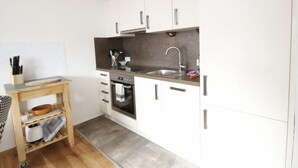A compact kitchen with white cabinets, a stainless steel sink, and a built-in oven. - Apartment Stein by Interhome (Pians)