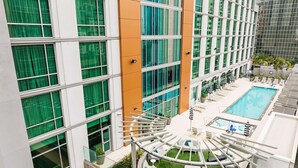 Un hotel moderno con piscina en la azotea, zona de estar al aire libre y terraza con paredes de cristal.