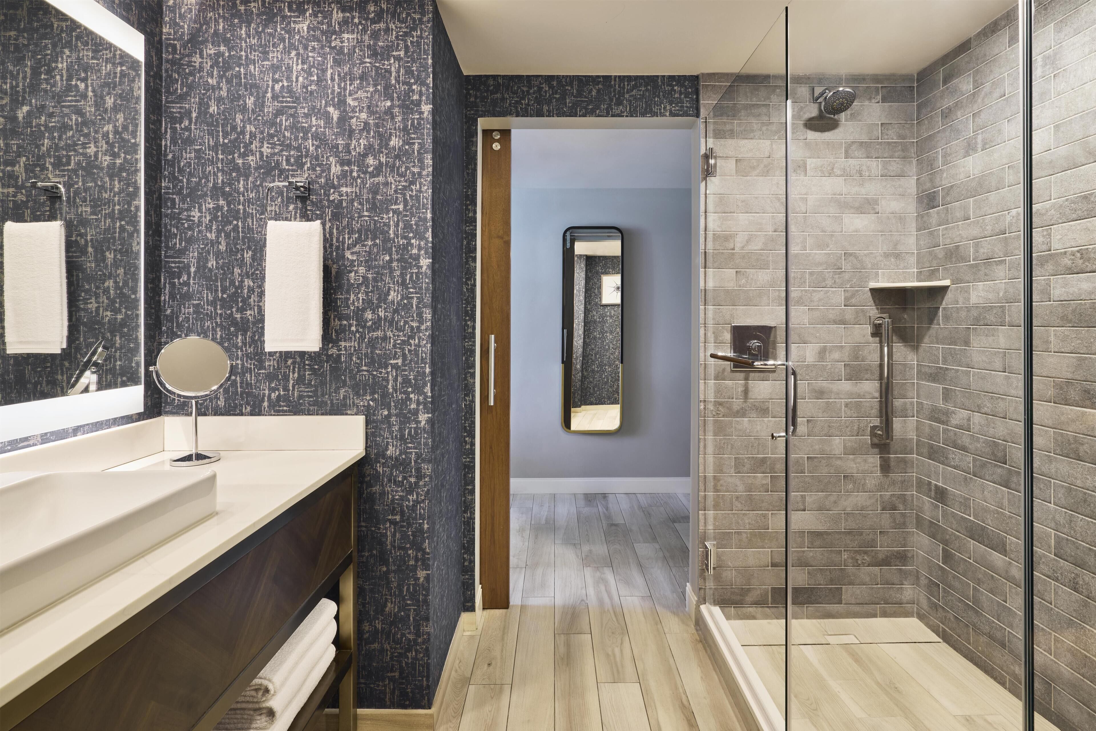 Un baño moderno con un espejo grande, un lavabo y una zona de ducha.
