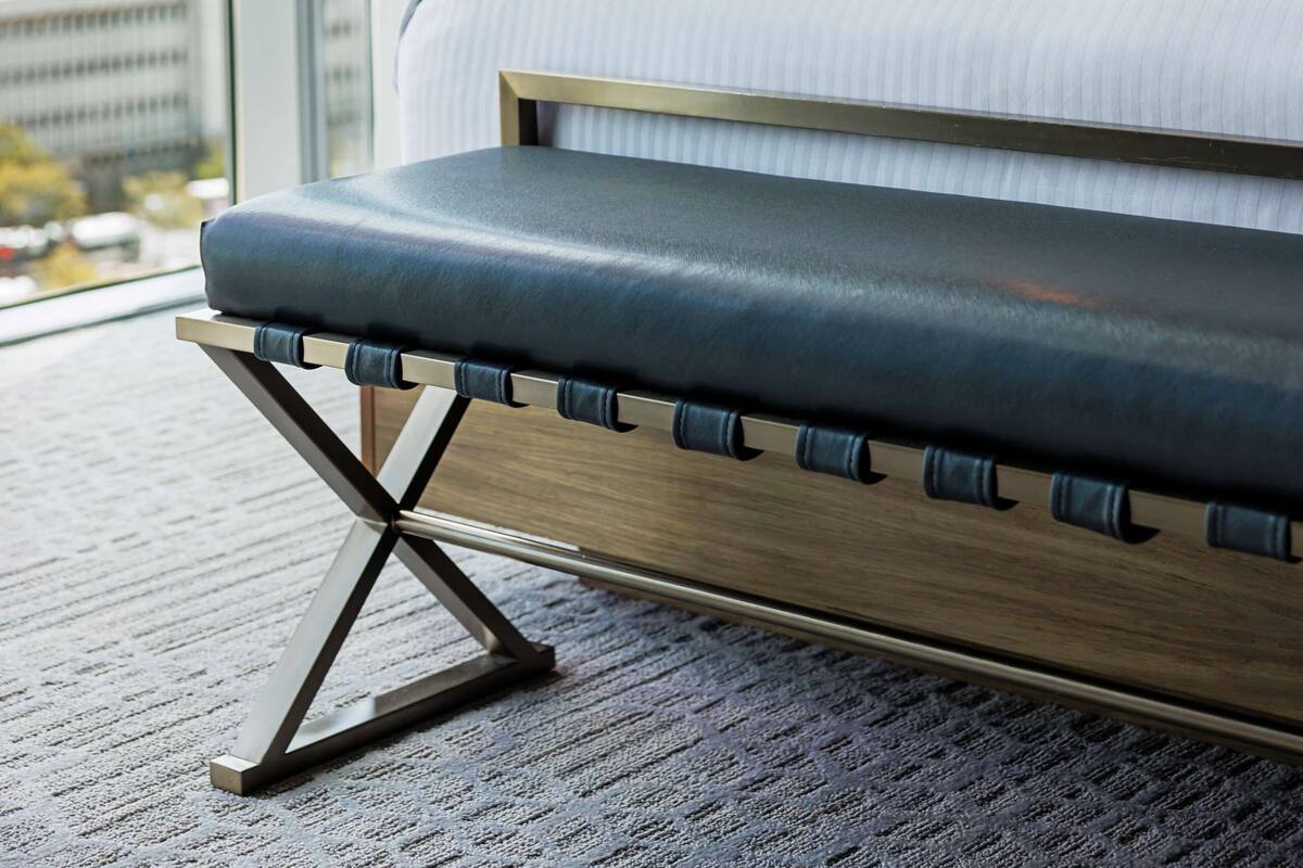 Una habitación de hotel moderna con una cama grande, vistas de la ciudad y una lámpara fijada a la pared.
