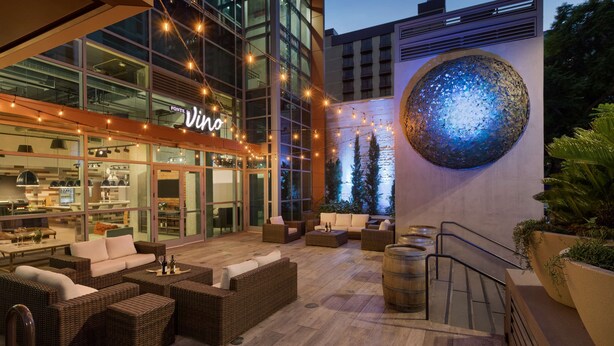 Un área de estar al aire libre con mobiliario de mimbre, un bar y una gran esfera decorativa.