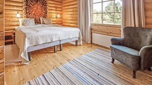 A log cabin bedroom with a bed, bedside lamps, a chair, a window, and a radiator. - Marttalanmäki by Interhome (Sysmä)