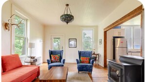Un salon comprenant un canapé, deux fauteuils, une table basse, une cheminée et un lustre.