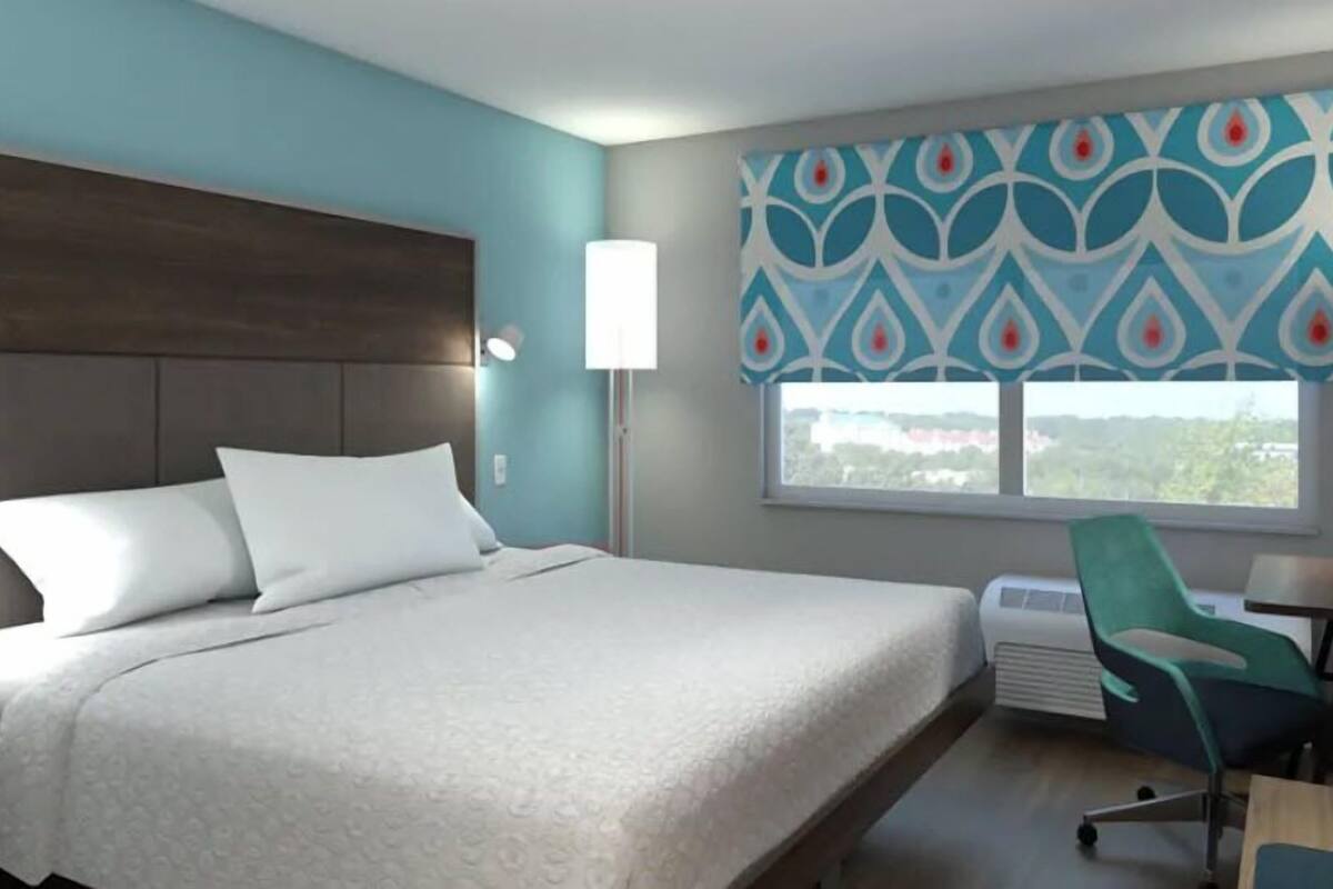 A hotel room with a bed, a desk, a chair, and a window with a view.