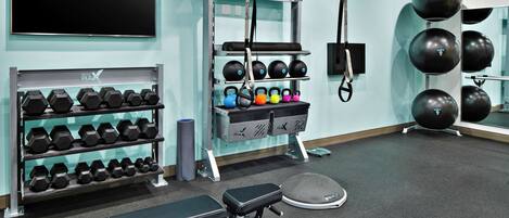 A gym with a bench, dumbbells, kettlebells, and exercise balls.