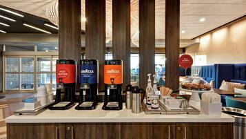 A coffee station with three coffee makers labeled "Lavazza" and "Hot Water" in a hotel lobby.