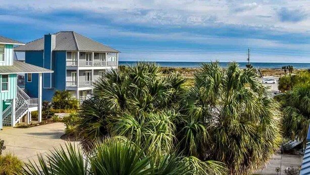 A beachfront property with a two-story building, a balcony, and a view of the ocean. - Perfect Family Vacation Spot in Perdido Key! Private beach access and pool. (Pensacola)
