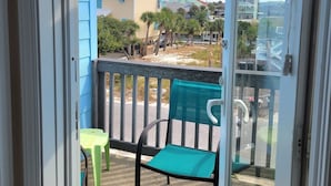 A balcony with a view of a beach and buildings. There are two chairs and a table on the balcony. - Perfect Family Vacation Spot in Perdido Key! Private beach access and pool. (Pensacola)