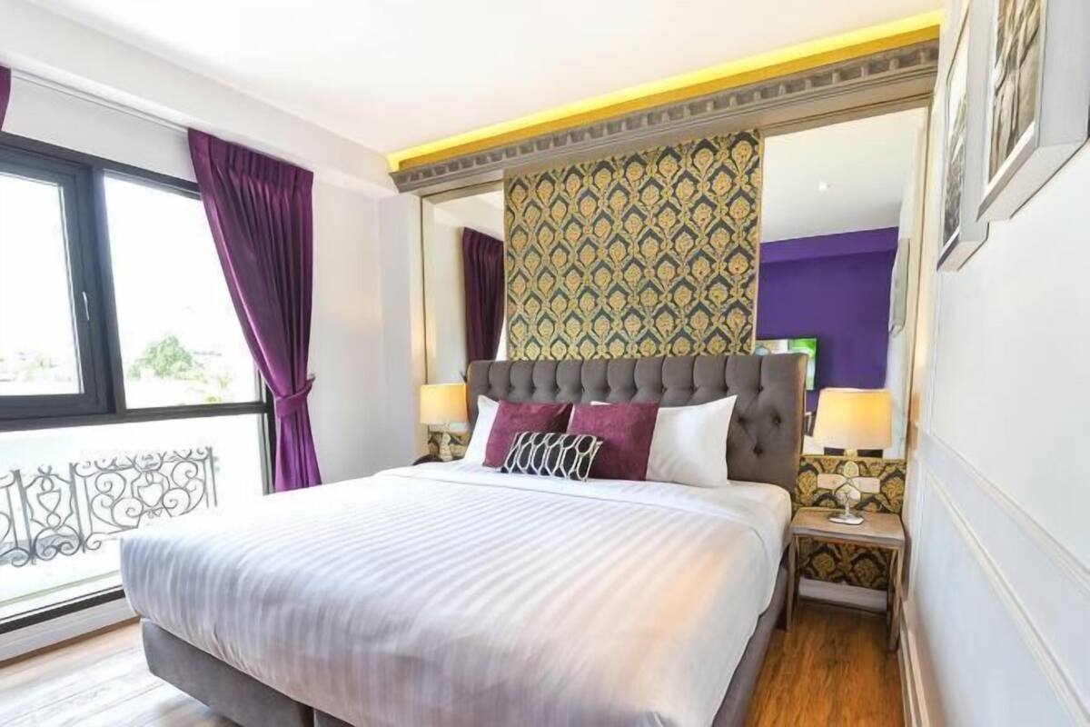 Une chambre d’hôtel avec un grand lit, une table de chevet, un miroir et une vue sur l’extérieur.