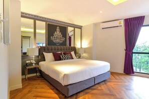 A hotel room with a large bed, a chandelier, a window with curtains, and an air conditioning unit. - Villa De Khaosan (Bangkok)