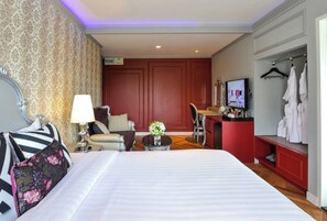 Una habitación de hotel con una cama grande, un escritorio, una silla, un televisor y un armario.
