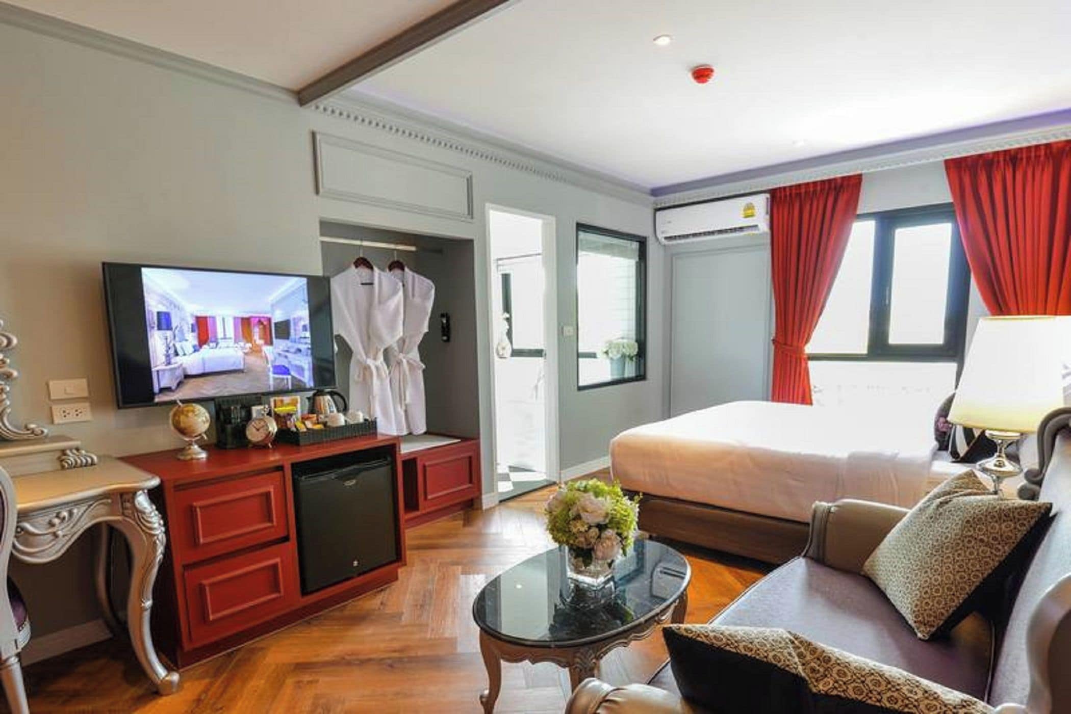 A hotel room with a bed, a television, a desk, and a seating area.