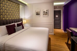 Ein Hotelzimmer mit einem großen Bett, einem Schreibtisch und einer Wand in Lila.
