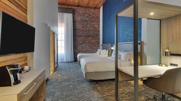 A hotel room with a large bed, a desk with a chair, a TV, and a coffee maker.