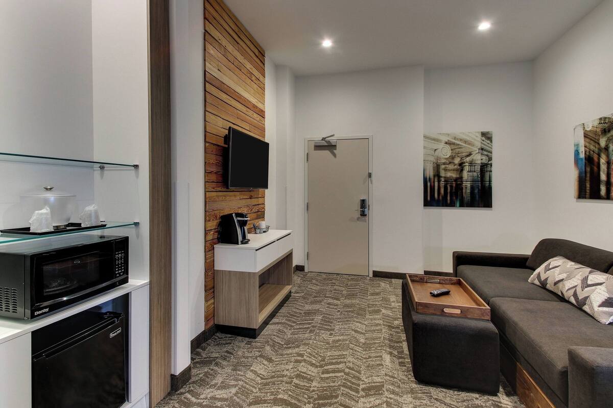 A modern living room with a sofa, a coffee table, a TV, and a microwave.