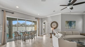 A spacious living area with a large sofa, a coffee table, and a dining area with chairs and a table. - 1/2 Block From Private Beach, 7 BR, Remodeled, Theater, Discounted Golf Cart (Miramar Beach)