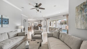 A spacious living room with a sofa, armchair, and coffee table. A ceiling fan and recessed lighting are visible. - 1/2 Block From Private Beach, 7 BR, Remodeled, Theater, Discounted Golf Cart (Miramar Beach)