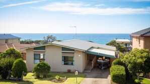 A residential house with a view of the ocean, a satellite dish, and a garage. - Kianga Parade Beach House (KIANGA)
