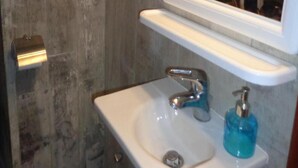 Ein Badezimmer mit weißem Waschbecken, einem Spiegel und einem Handtuchspender.