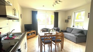 Eine moderne Küche mit Essbereich, einer Couch und einem Fernseher.
