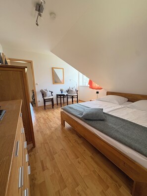 Una camera da letto con un letto di legno, una scrivania, una sedia, un tavolino e una finestra con tende.