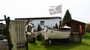 A boat tied to a dock with a net and life preserver, a flag, and a building in the background. - Holidays directly on the water with great additional services (Ziemitz)