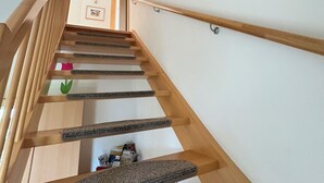 A wooden staircase with a handrail, a wall-mounted picture frame, and a small table with items on the landing. - Holidays directly on the water with great additional services (Ziemitz)