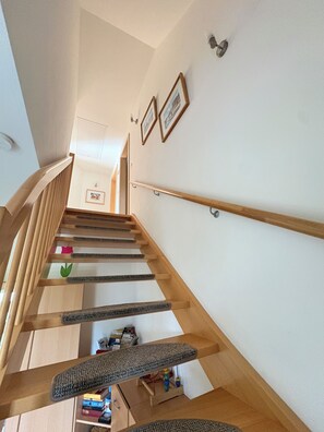 A wooden staircase with a handrail, a wall-mounted picture frame, and a small table with items on the landing.